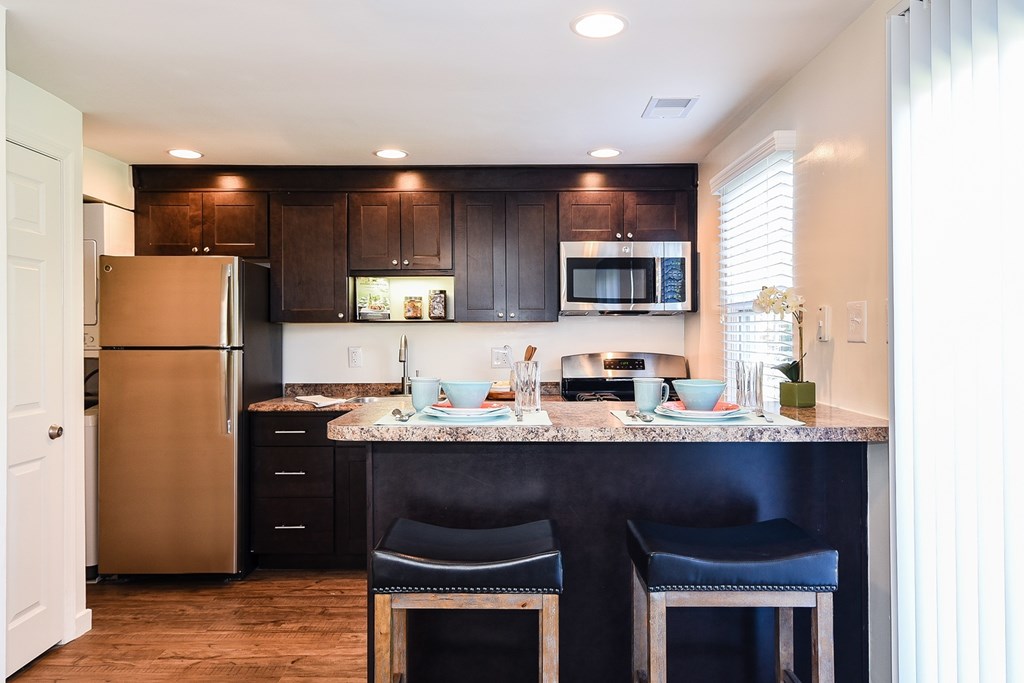 A kitchen with a granite countertop and black chairs.