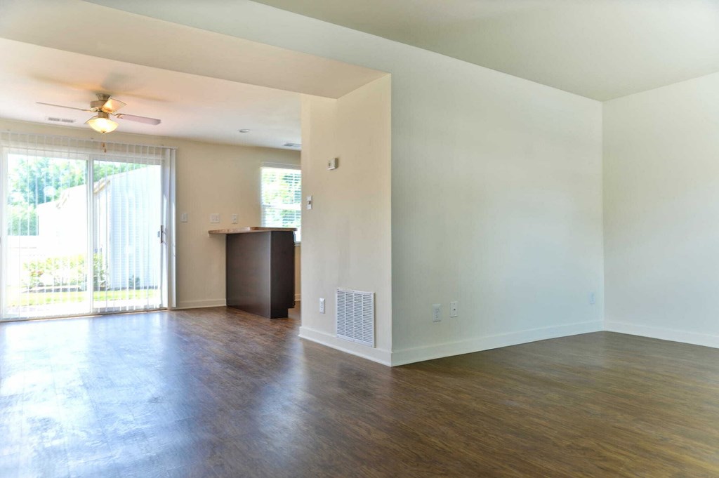 an empty living room with wood flooring and a ceiling fan