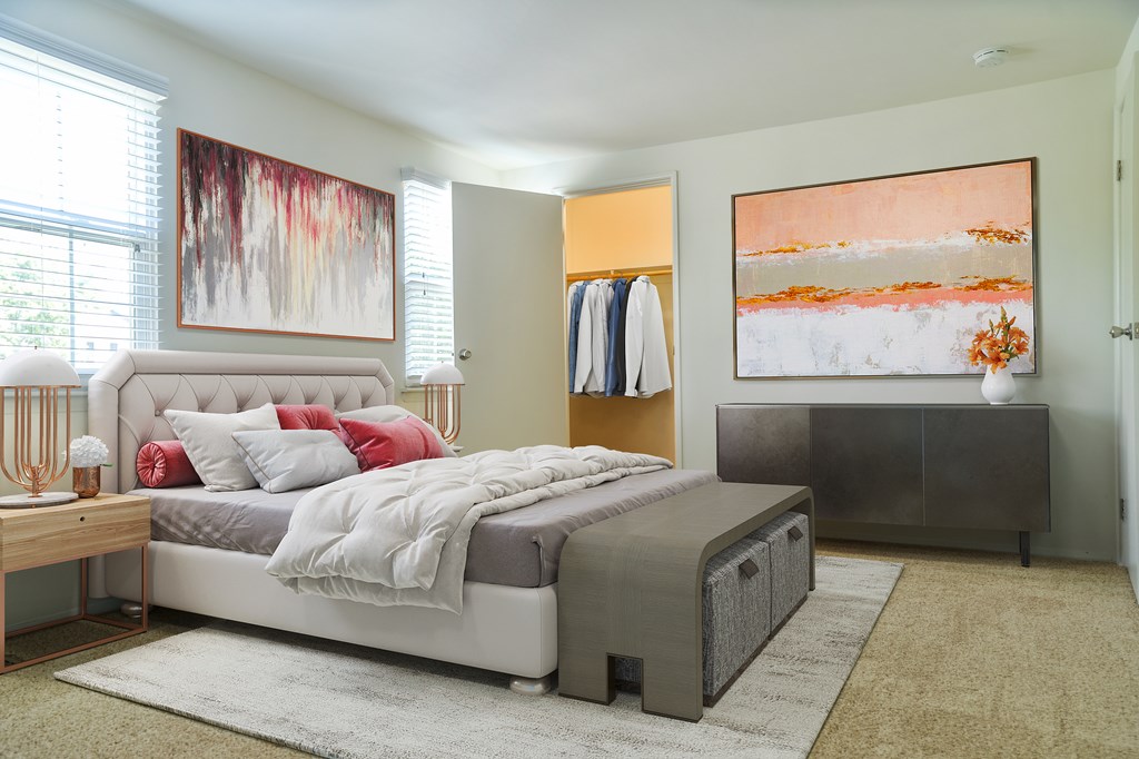 A bedroom with a large bed and a painting on the wall.