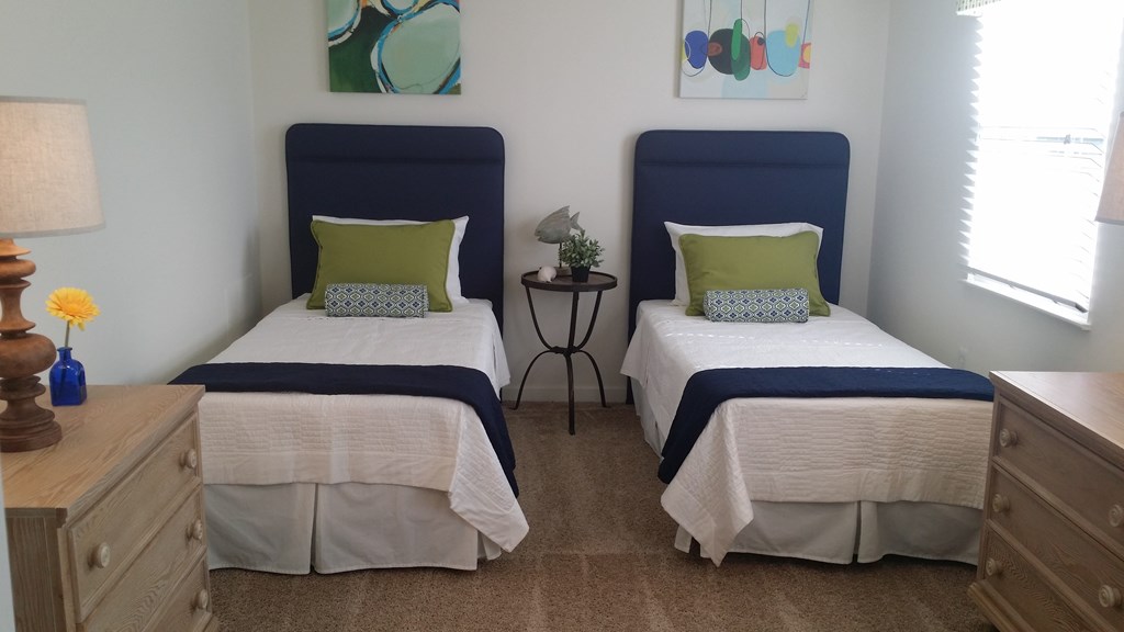 Two twin beds with blue headboards and white bedding in a room.