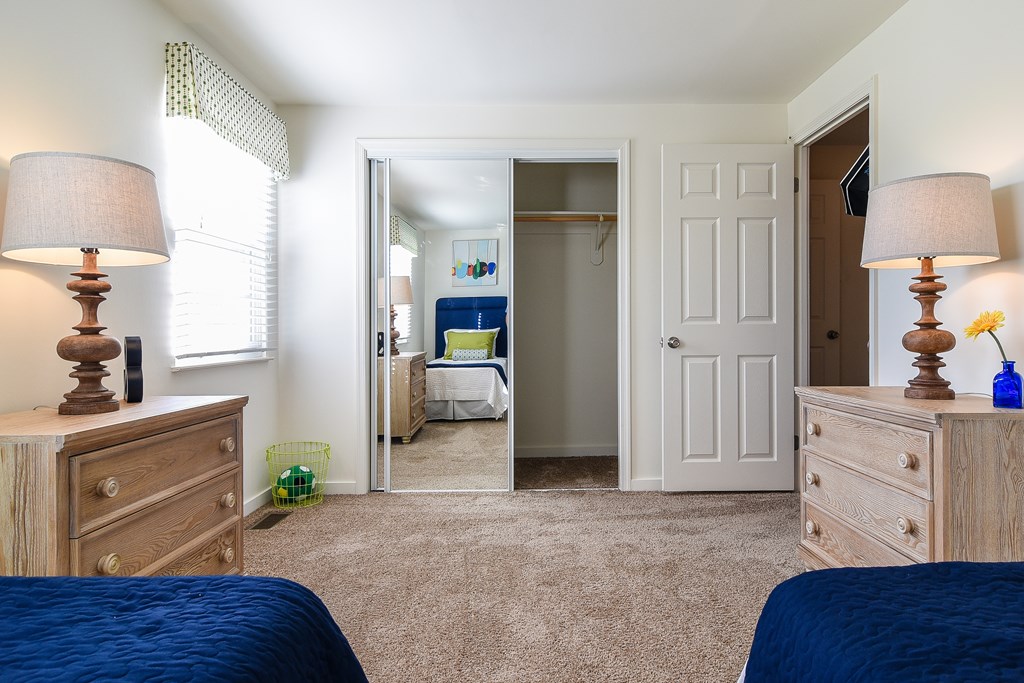 A bedroom with two beds, two dressers, and a mirror.
