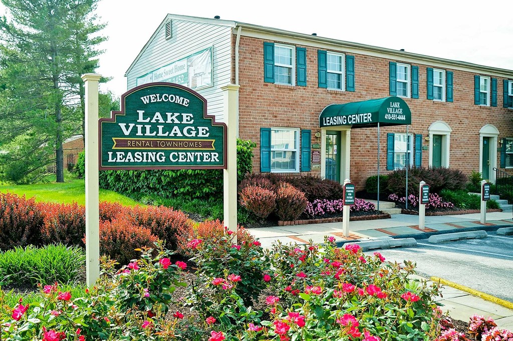 a sign for the lake village leasing center in front of a brick building