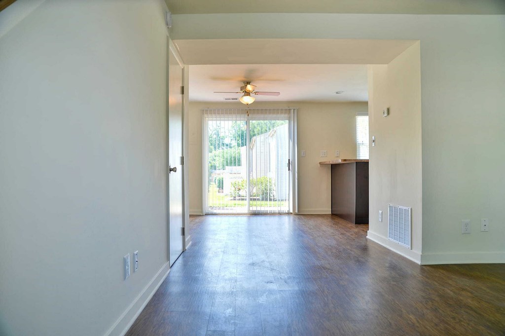 an empty living room with a ceiling fan and a door to a patio
