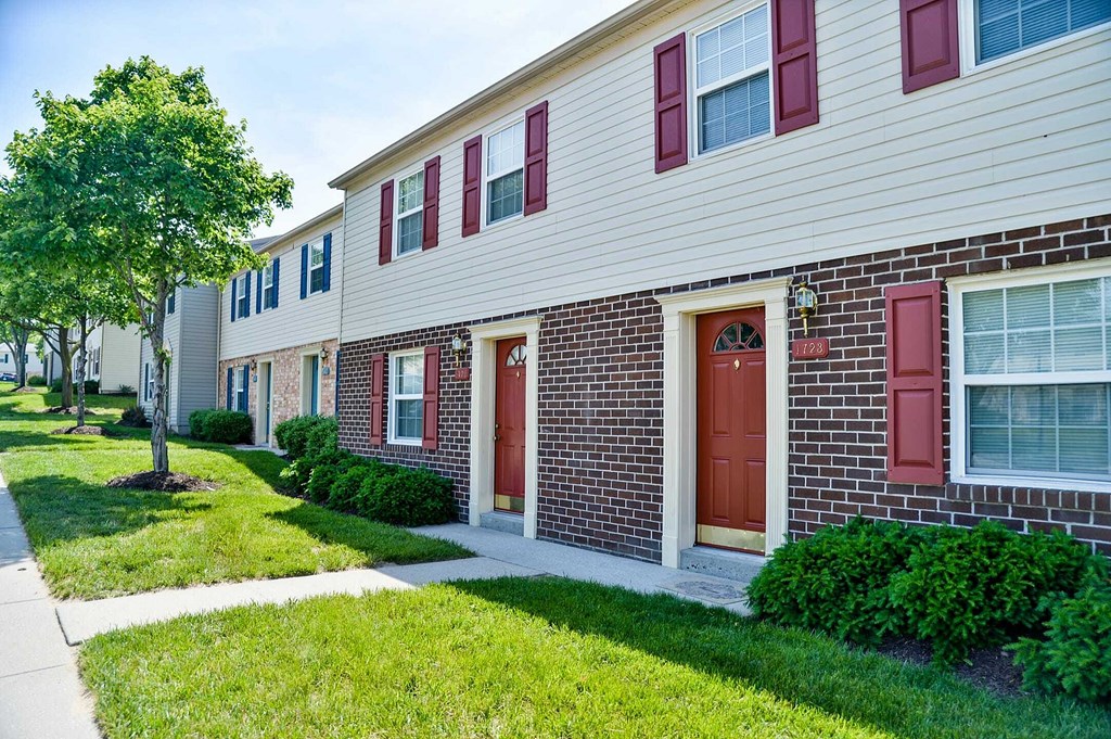 a brick and white building with red doors and a sidewalk