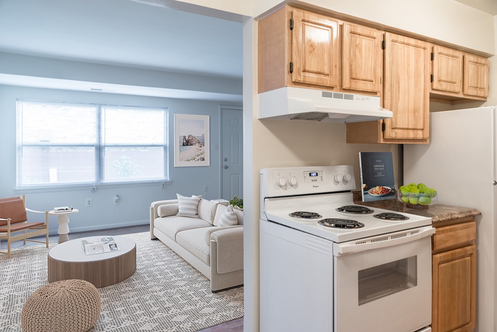 A kitchen with a stove top oven and a refrigerator with wooden cabinets above it.