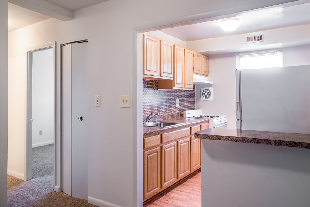 A kitchen with wooden cabinets and a white fridge.
