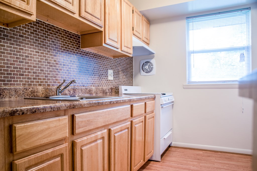 A kitchen with wooden cabinets and a brick backsplash.