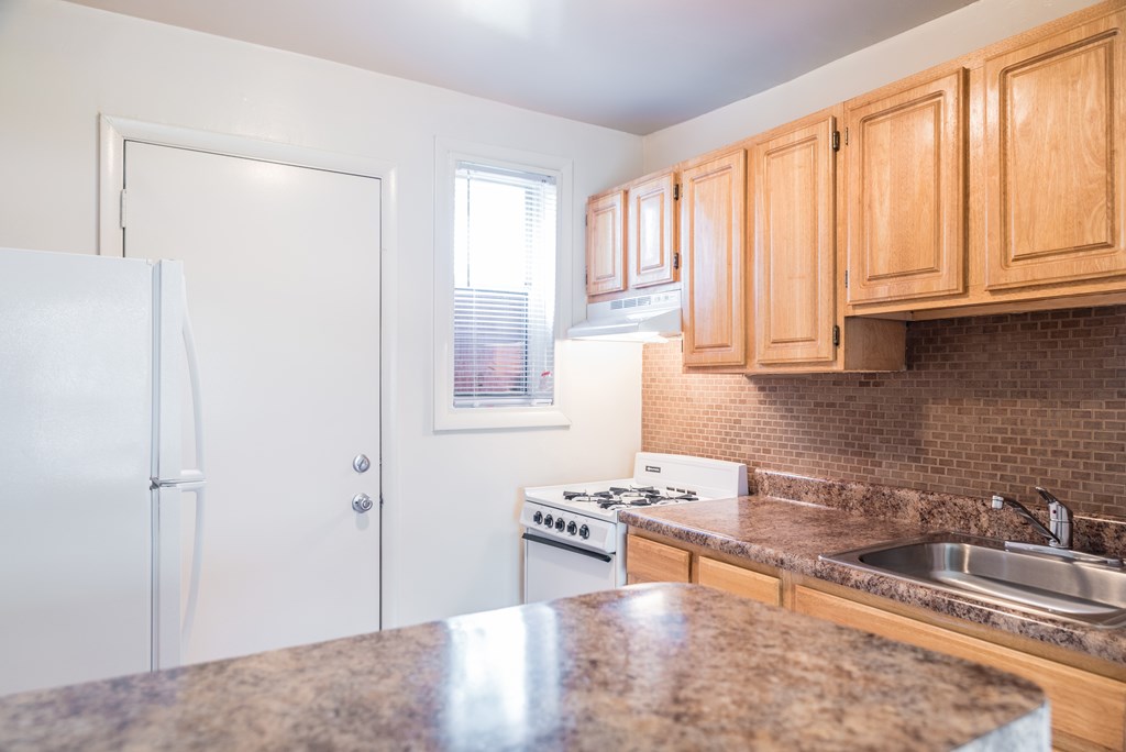 A kitchen with a granite countertop and wooden cabinets.