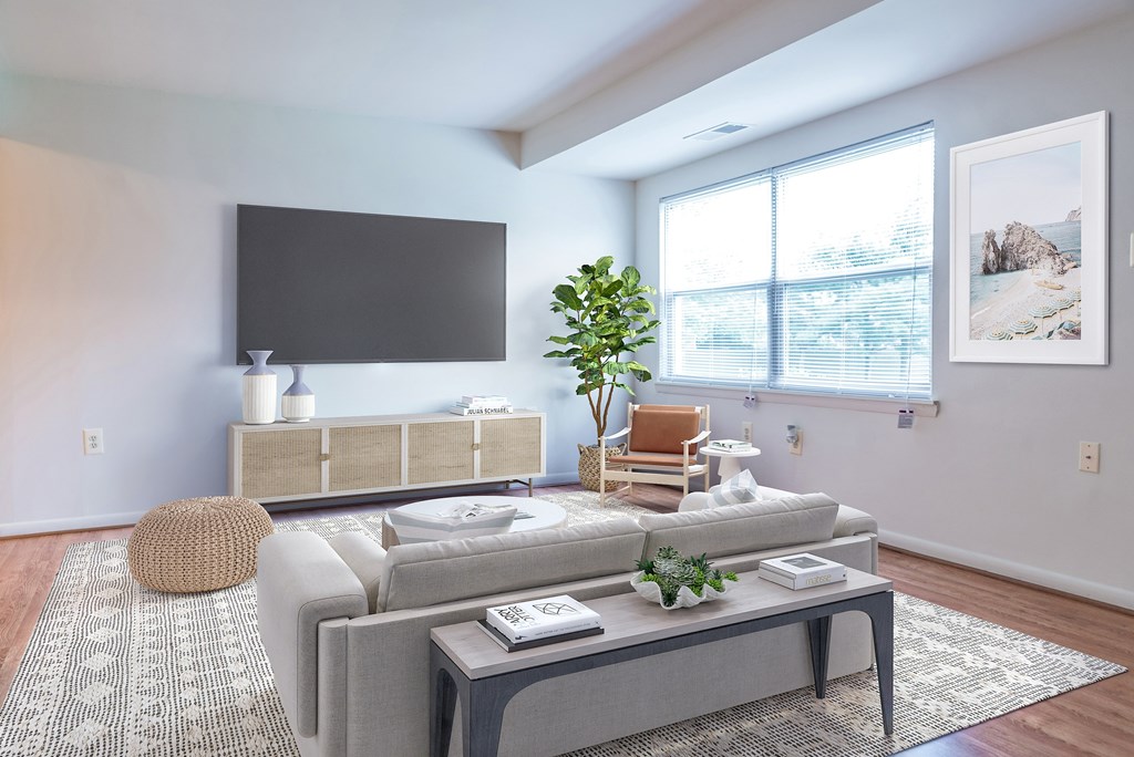 A living room with a grey sofa, a coffee table, and a flat screen TV mounted on the wall.