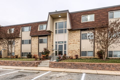 A building with a brown roof and tan walls with a parking lot in front.