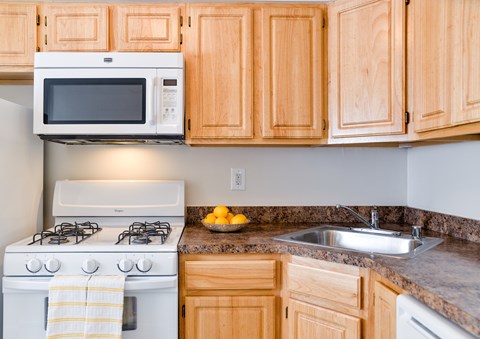 A kitchen with a white stove and a white microwave above it.
