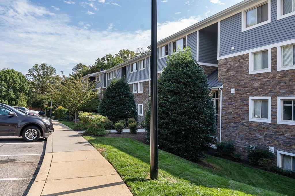 A street view of a residential area with a car parked on the sidewalk.