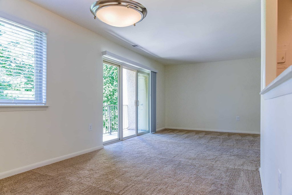 an empty living room with a sliding glass door to a patio