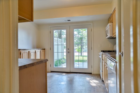 A kitchen with a white door leading to a backyard.