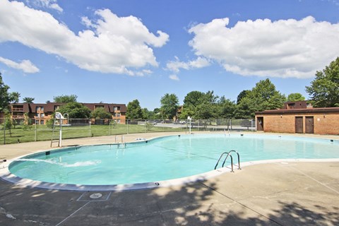 A large swimming pool with a blue tinted water and a white cloud in the sky.