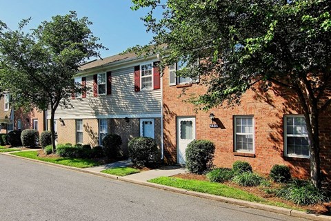 A row of houses with a tree in front of the first one.
