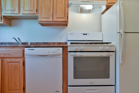 A white dishwasher is next to a white oven in a kitchen.