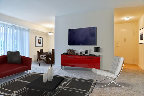 A living room with a red couch, a black coffee table, and a flat screen TV mounted on the wall.