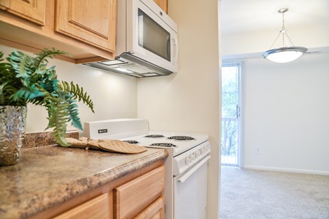 A kitchen with a white stove and microwave above it.