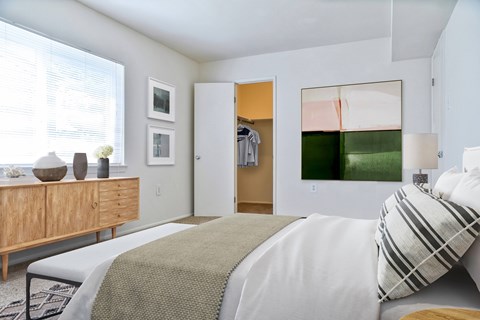 A bedroom with a bed, a dresser, and a painting on the wall.