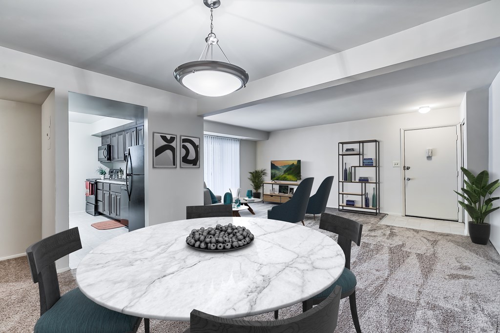 A white marble dining table with a bowl of decorative rocks in the middle and green chairs around it.