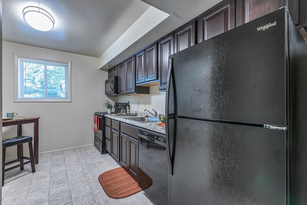 A black refrigerator in a kitchen with a window.