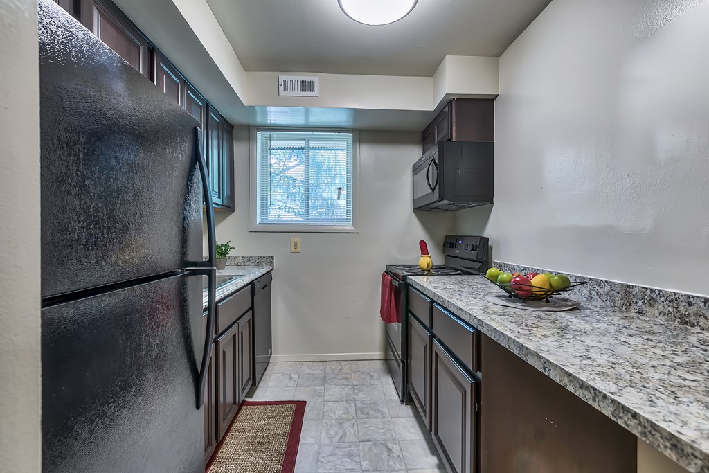 A kitchen with a black refrigerator and a window.
