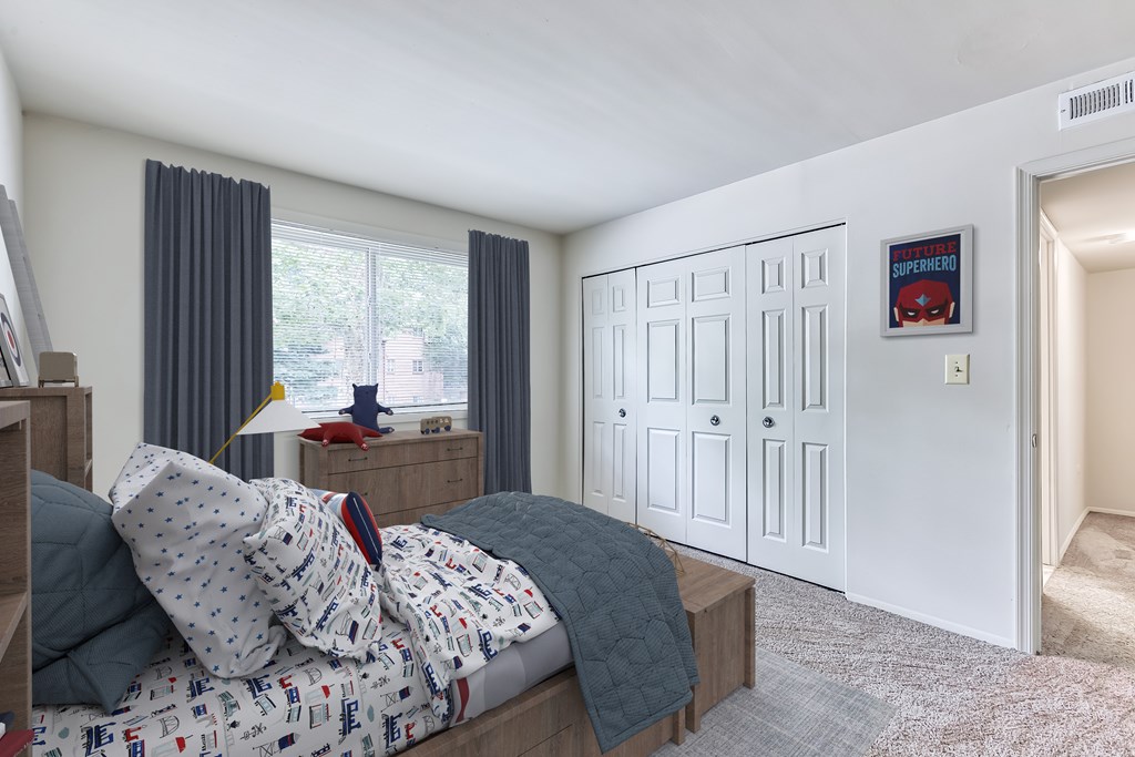 A bedroom with a bed, nightstand, and a poster on the wall.