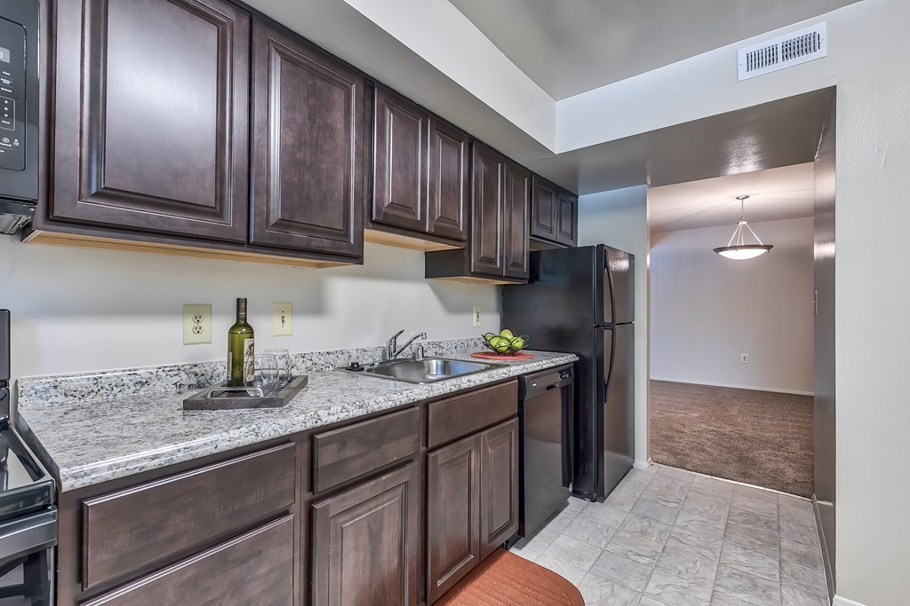 A kitchen with dark brown cabinets and a black refrigerator.
