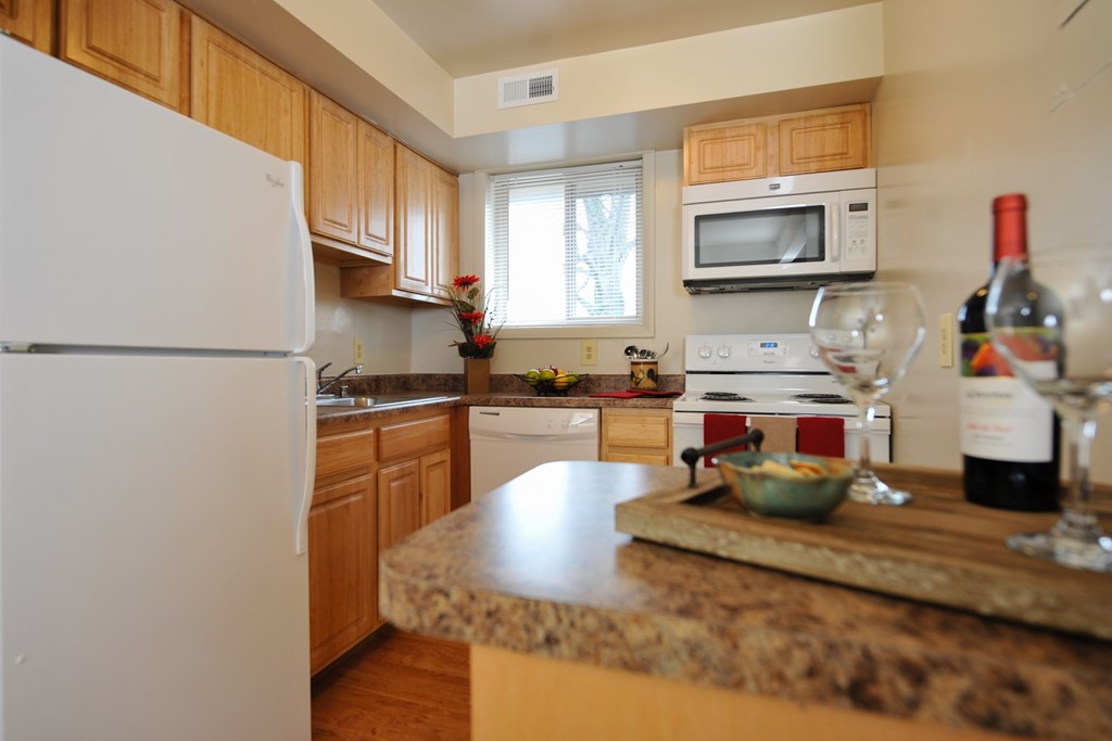 A kitchen with a granite counter top and a white refrigerator.