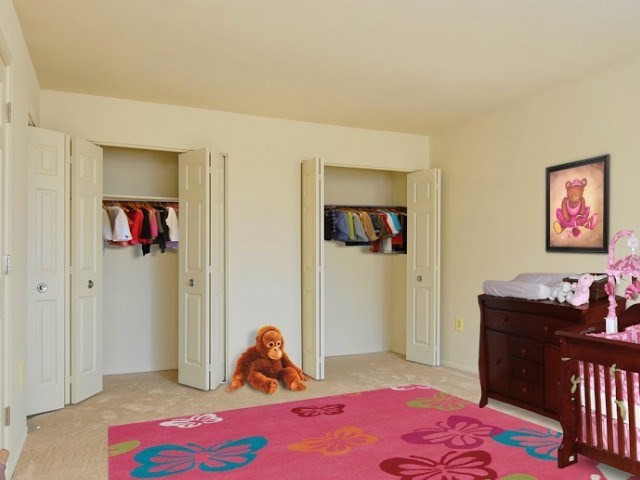 A baby's room with a pink rug and a teddy bear.