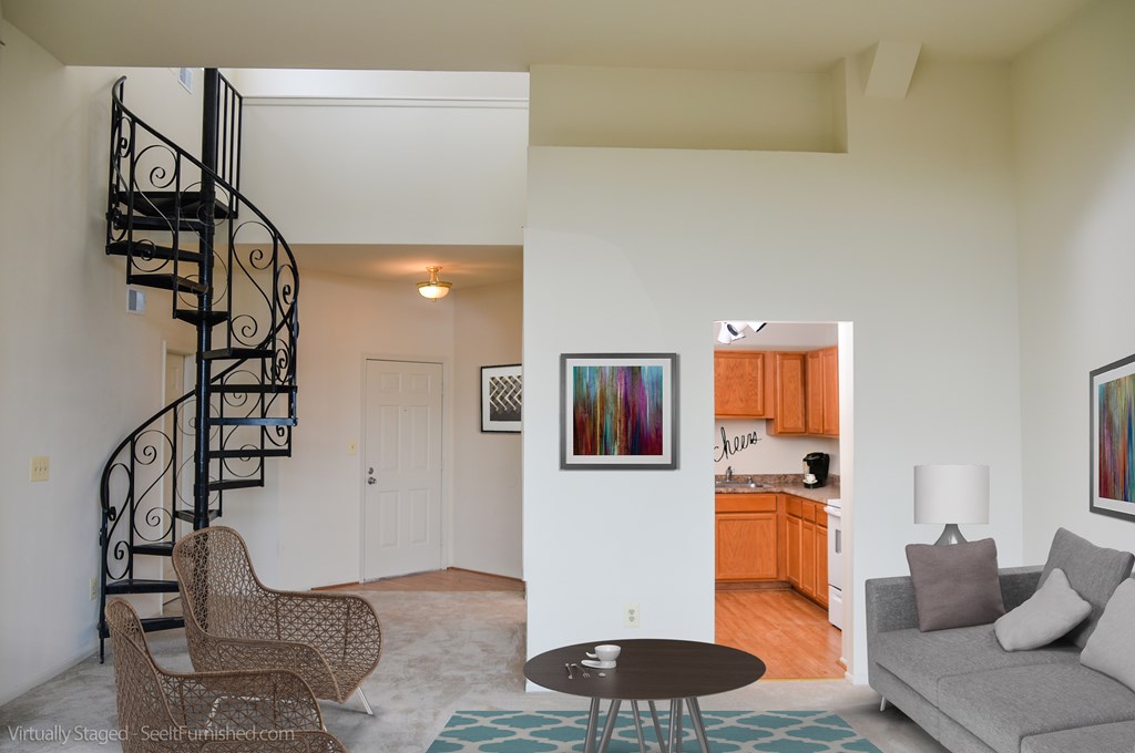 A living room with a spiral staircase and a grey couch.