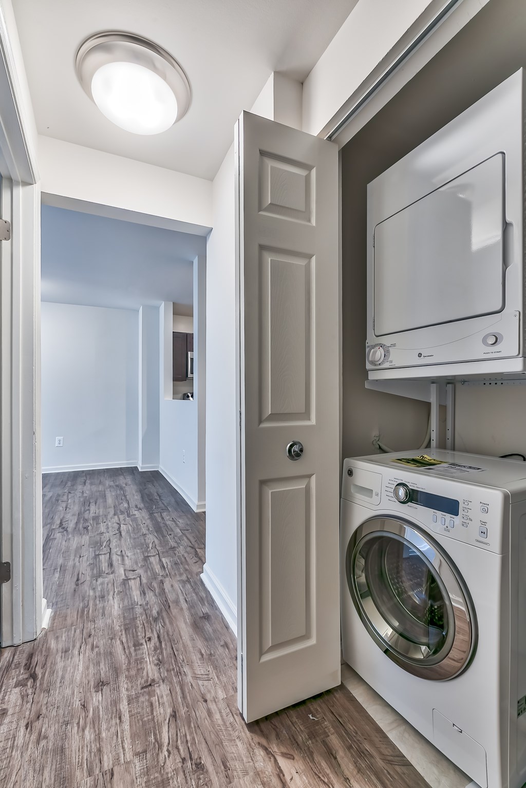 A white washing machine is in a small room with a door open.