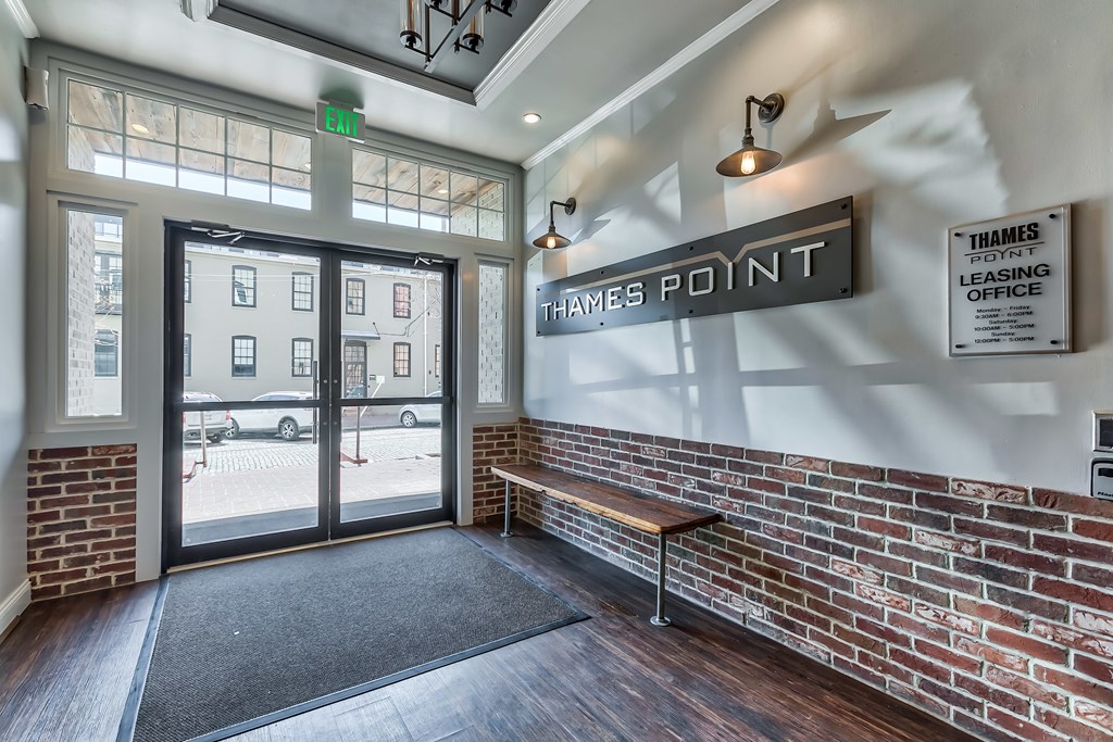 The lobby of a leasing office with a bench and a glass door.