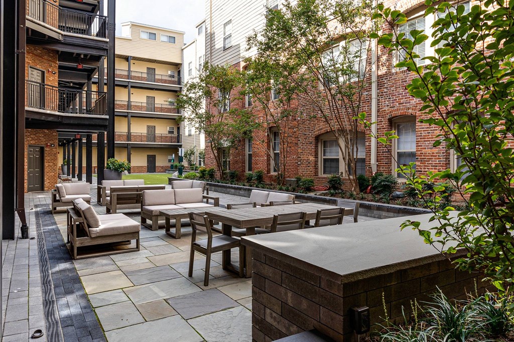 A patio with a table and chairs is surrounded by buildings and trees.