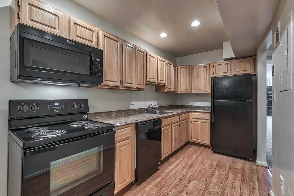 A kitchen with black appliances and wooden cabinets.