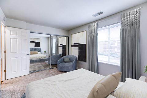 A bedroom with a large bed and a grey chair.