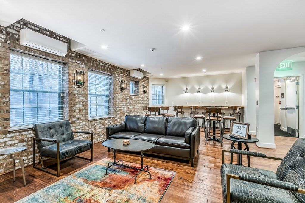 A living room with a brick wall and a variety of seating options.