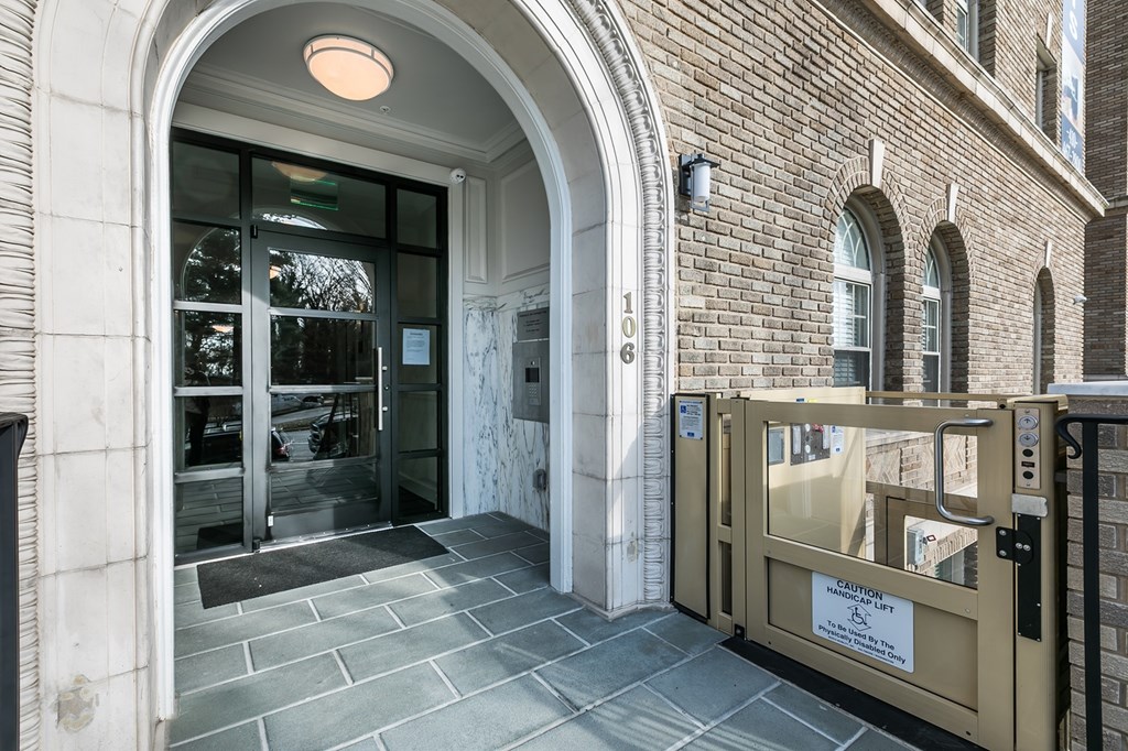 A building entrance with a glass door and a sign on the gate.