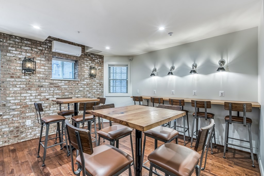 A dining area with a brick wall and a long table with chairs.