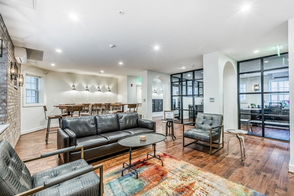 A living room with a black couch and a rug.