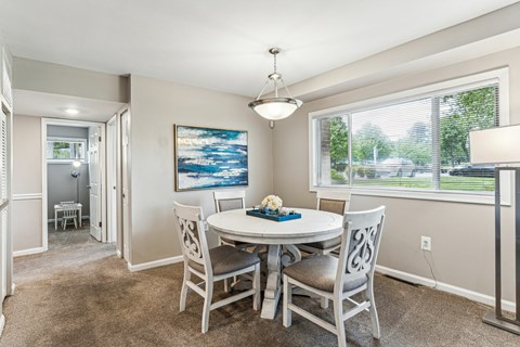 A dining room with a white table and chairs.