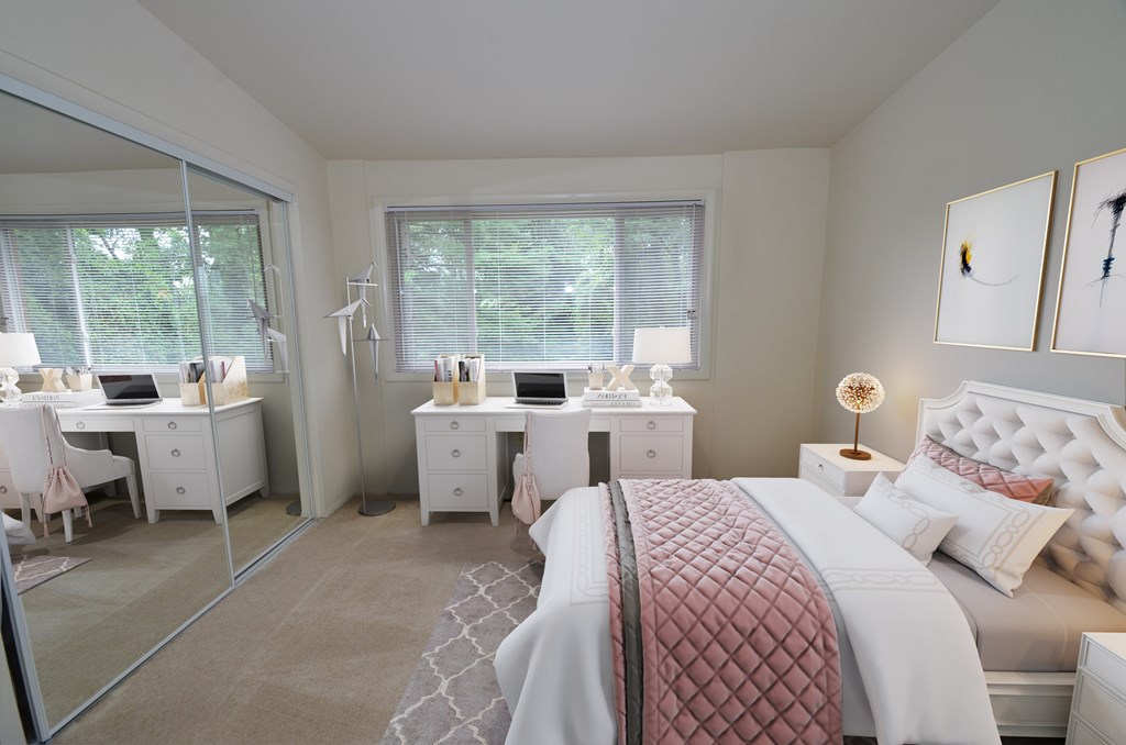 A bedroom with a large bed and a desk with a laptop.