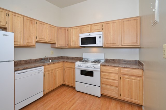 A kitchen with wooden cabinets and white appliances.
