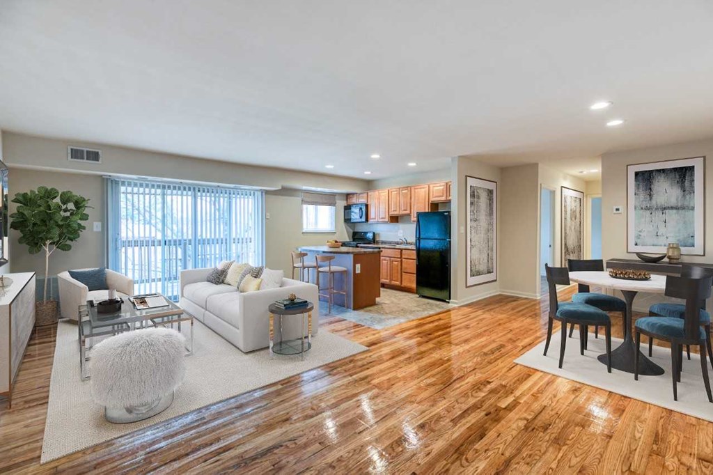 A spacious living room with a white sofa set and wooden flooring.