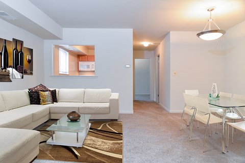 A white couch with a glass coffee table in front of it.