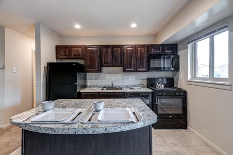 A kitchen with black appliances and brown wooden cabinets.