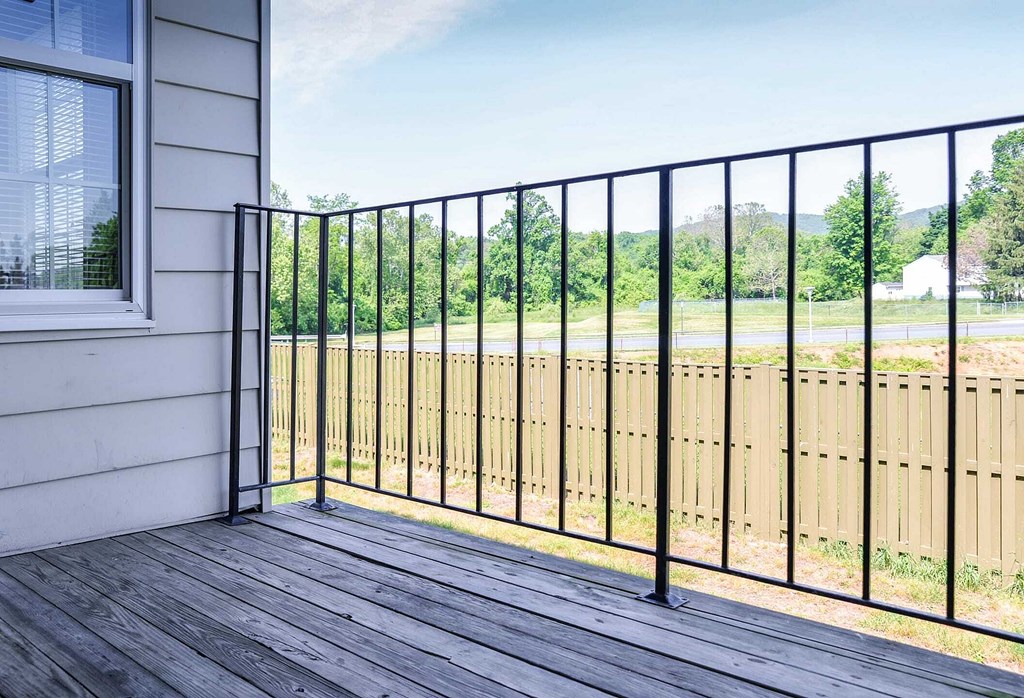 a balcony with a fence and a view of a field