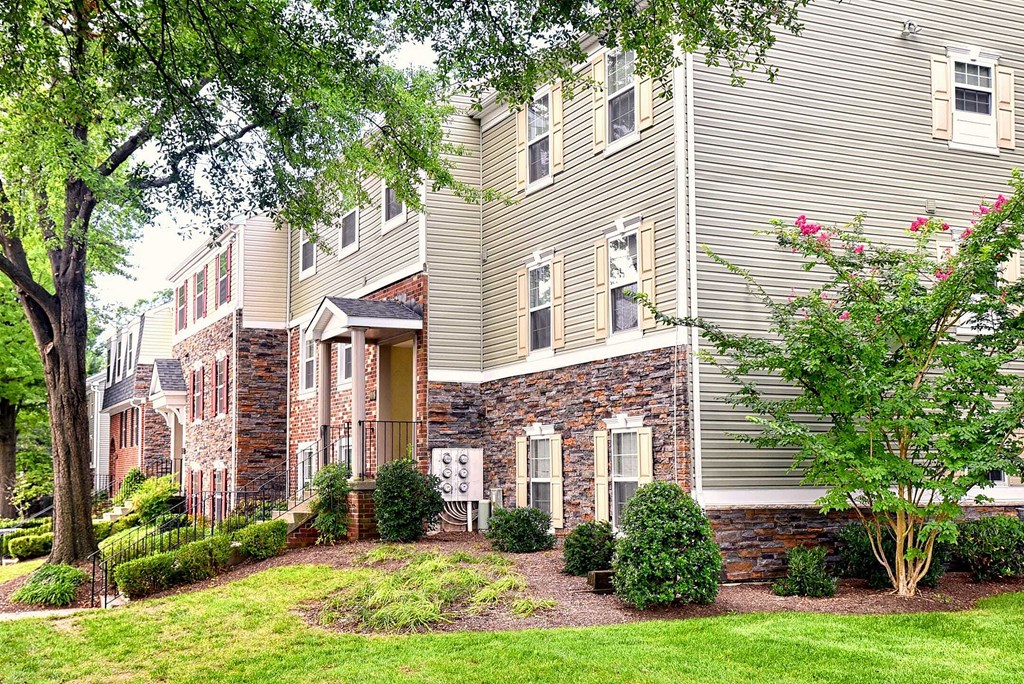 the front of a house with a lawn and trees