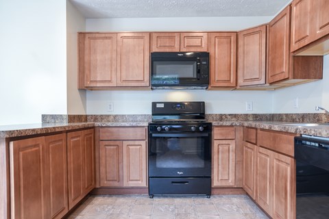 A kitchen with wooden cabinets and a black stove.